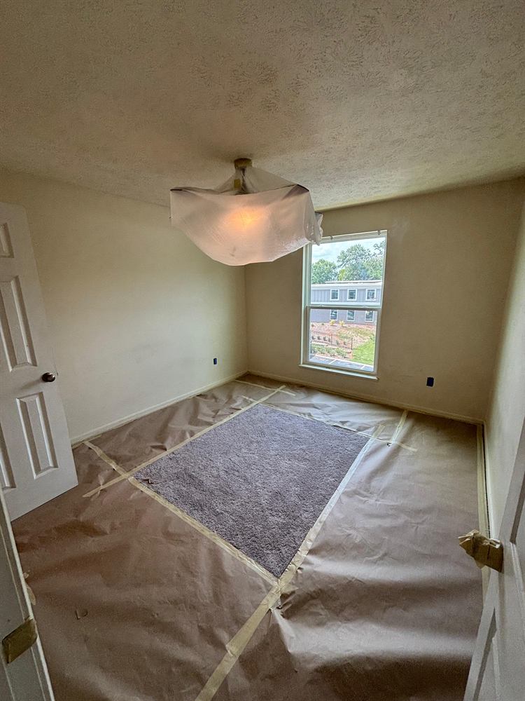 Bedroom floor fully masked with drop cloths during surface preparation