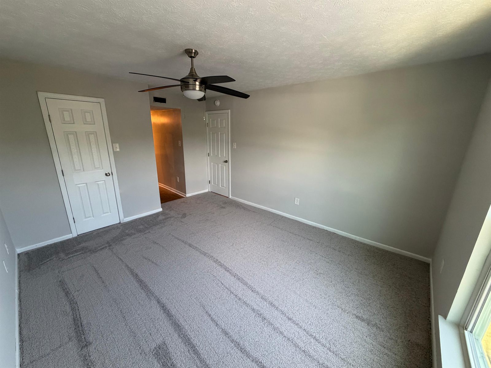 Turned apartment living area with freshly painted walls, white trim and vacuumed grey carpet