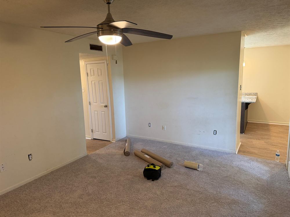 Apartment living area during turnover with paint roller and materials on the floor