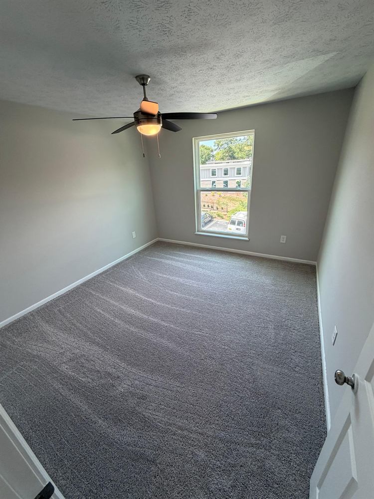Bedroom with sharp ceiling cut line, ceiling fan and vacuumed carpet